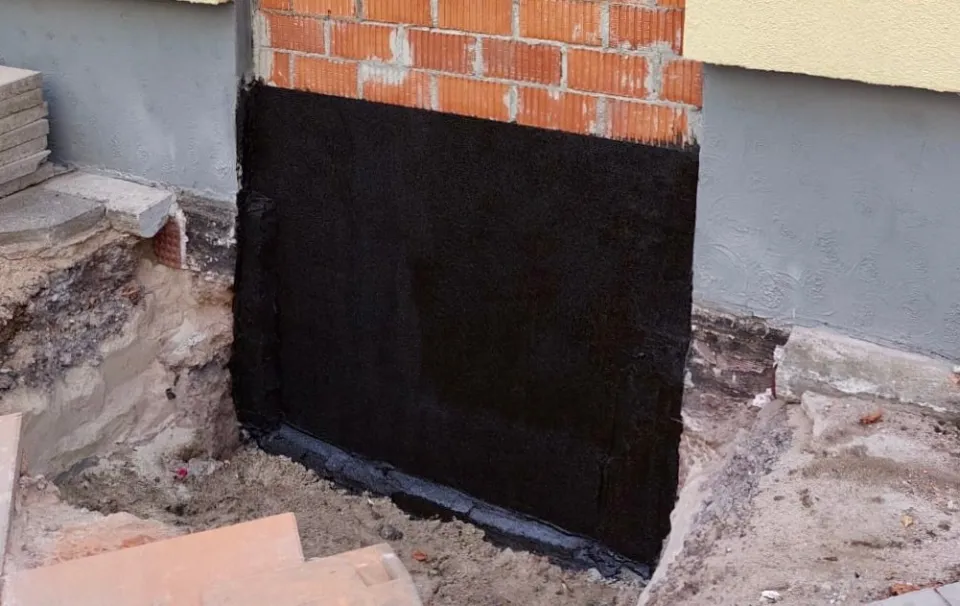 Schwarze Abdichtung an einer freigelegten Außenwand